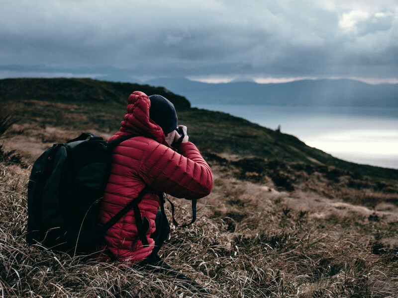 Person in red puffer jacket taking photos in the wilderness